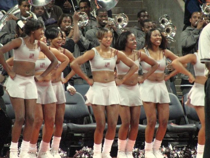 a group of cheerleader in white outfits are posing for a po with their band mates