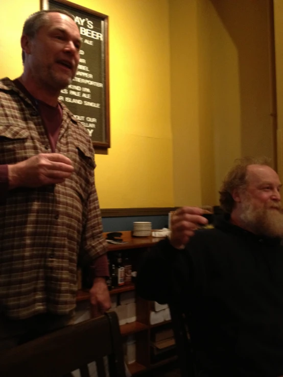 two men standing near a wall holding wine glasses