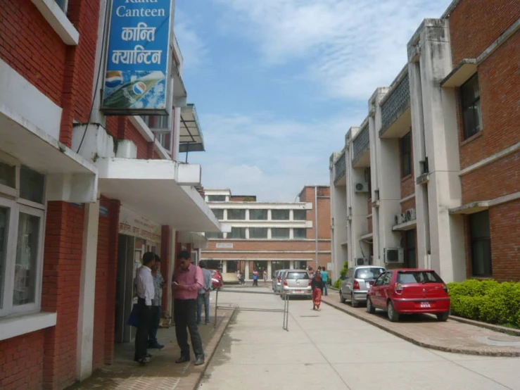 people walking towards a building with two cars parked on it