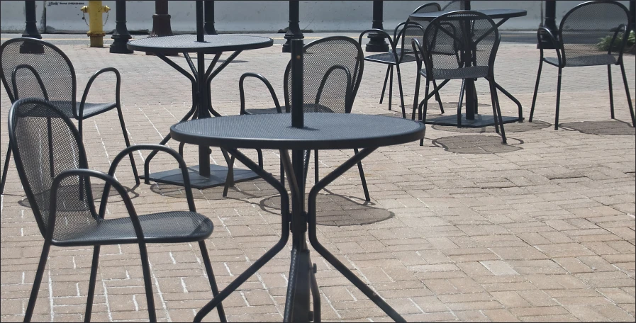 a table on the sidewalk surrounded by chairs