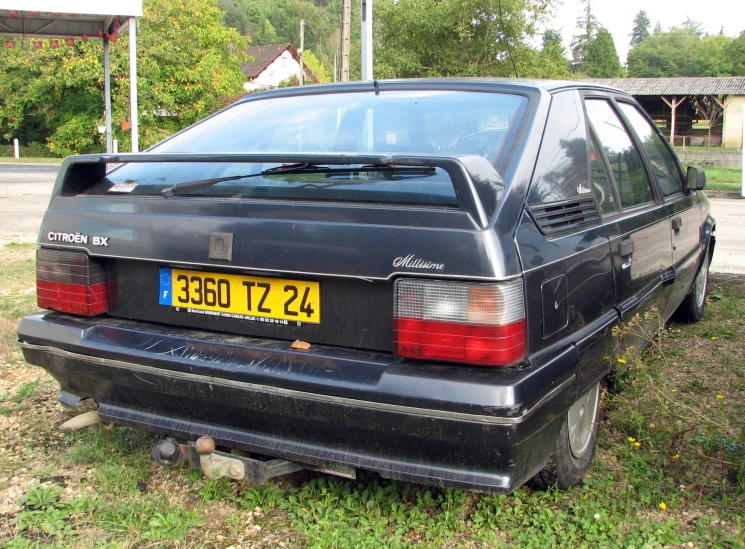 an old, dirty car sits on the grass