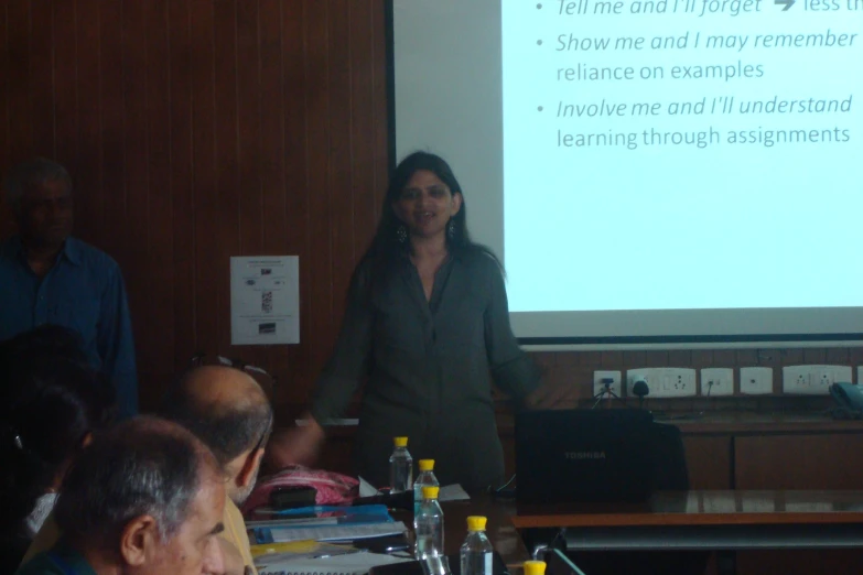 a woman standing in front of a white projection screen