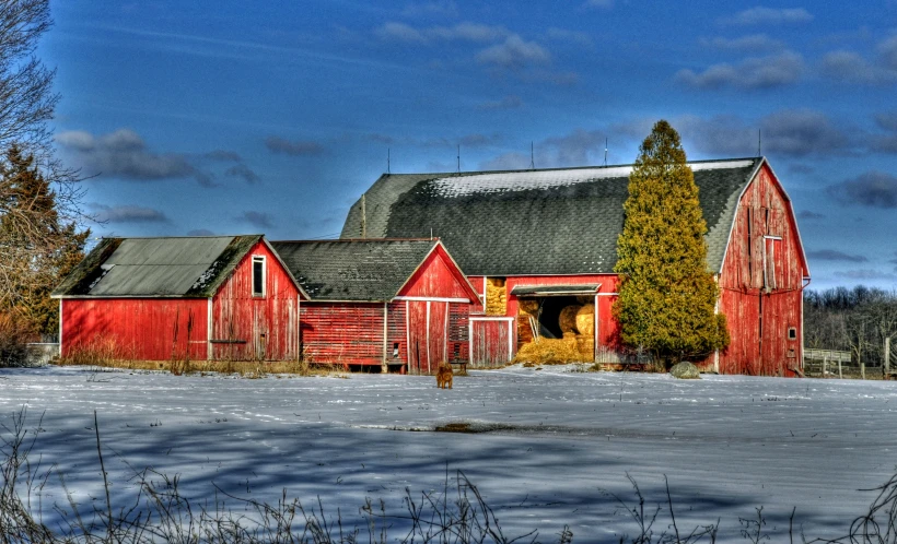 there is a snow covered field with an old red barn