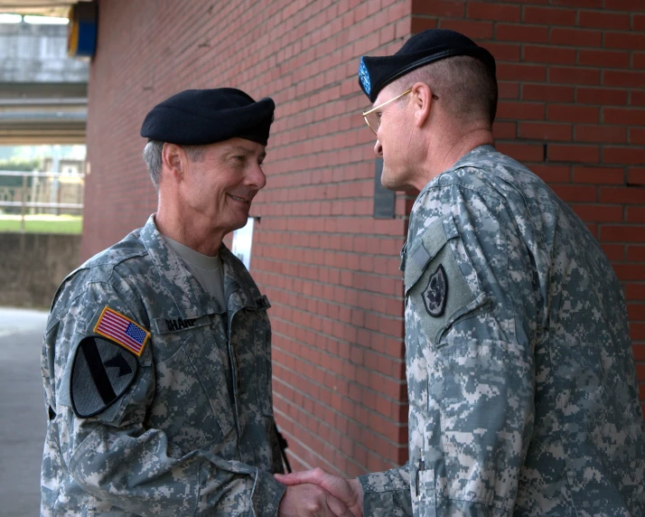 two soldiers shaking hands in front of a brick wall