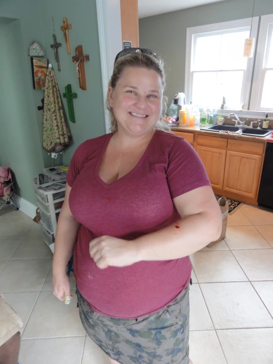 a woman smiling as she stands in the kitchen