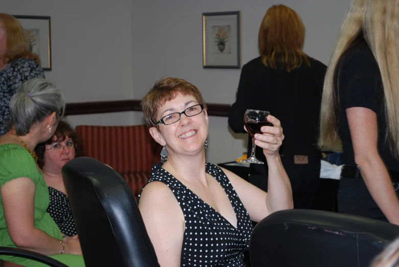 the woman is sitting in a chair and smiling with a glass in her hand