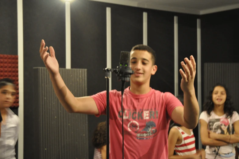 a young man holding his hands up in front of a microphone