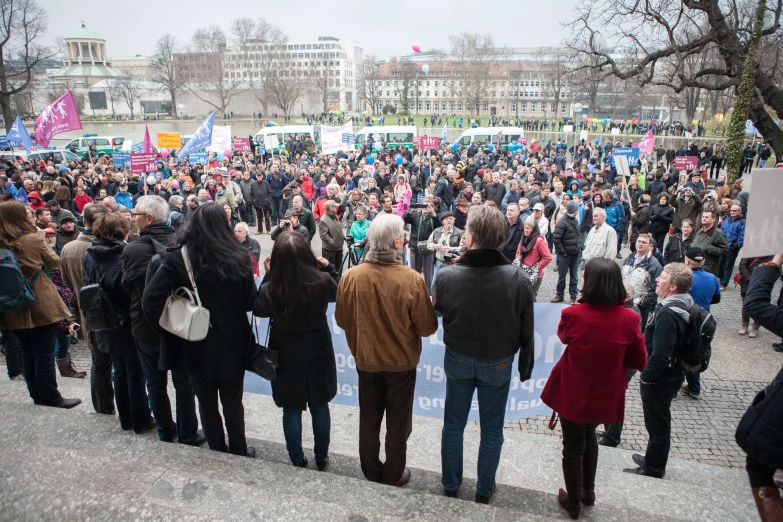 people in a crowd on the sidewalk with signs