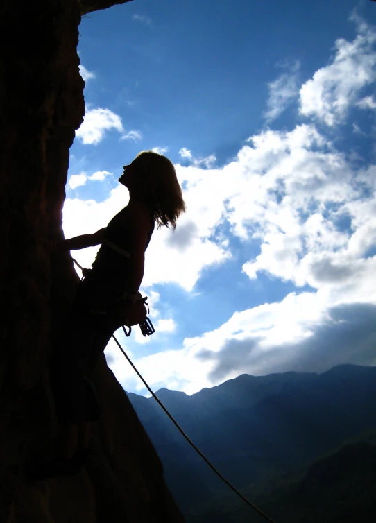 the silhouette of a woman on top of the cliff