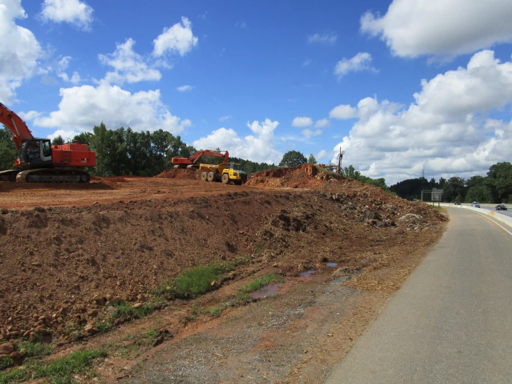 a road with construction equipment on it under a cloudy sky