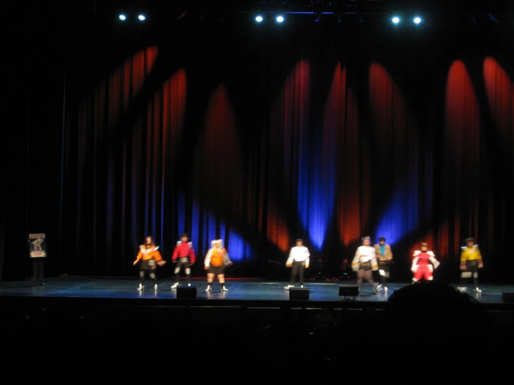 a performance of people dancing on stage with a spotlight from behind