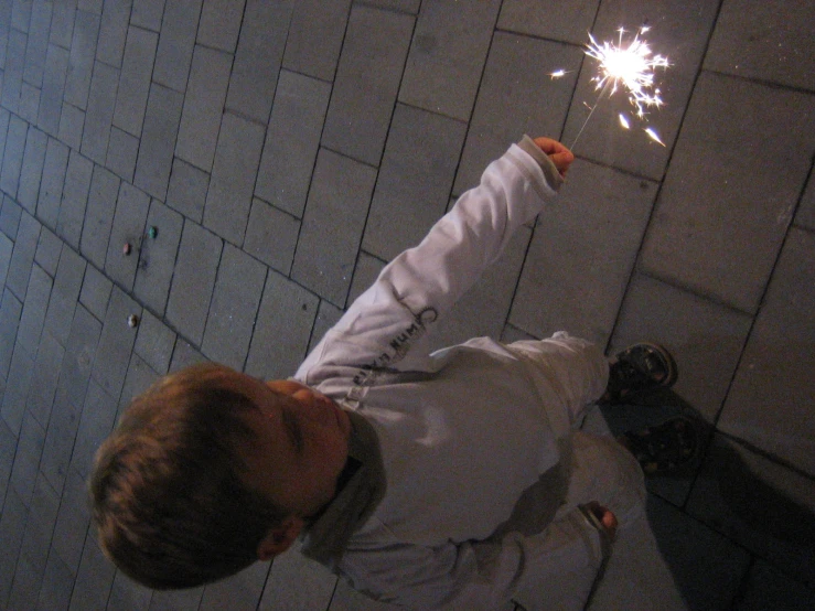 the little boy is standing outside with his sparkler
