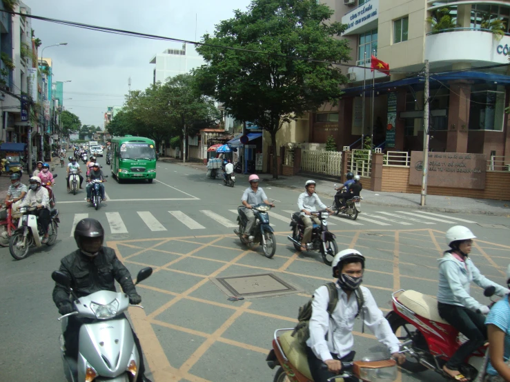 some people on motorcycles some buildings and green buses