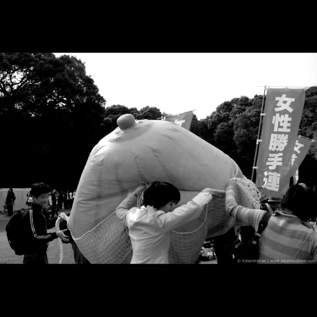 a large stuffed bear with people holding the back of it