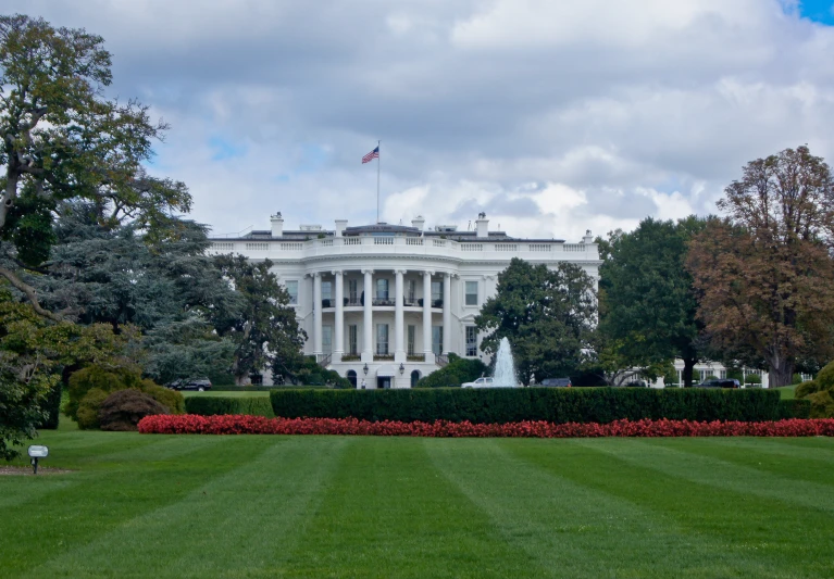 the white house and garden with red flowers