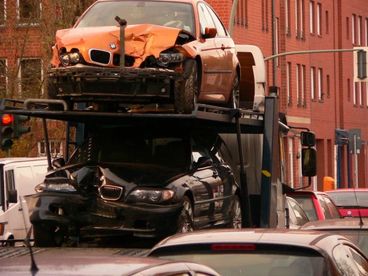 a large truck carrying a wrecked orange car