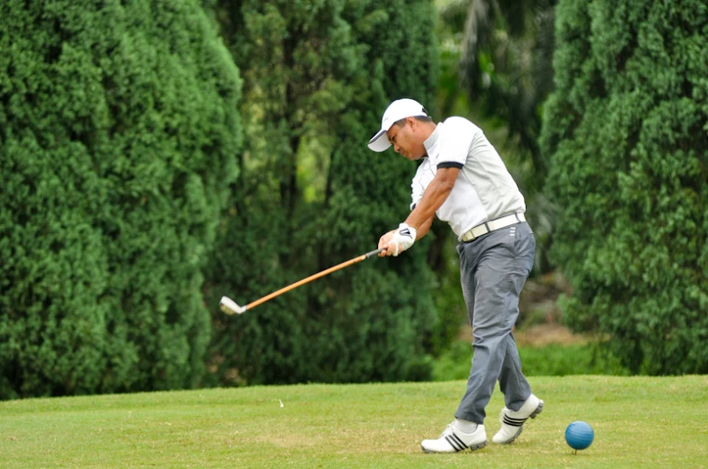 a man playing golf with a ball on a golf course