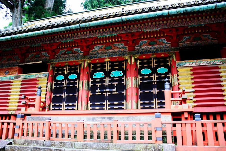 a red building with two ornately carved windows and ornate doorways