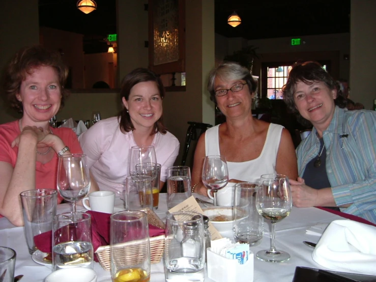 three women pose for a po with a group of empty wine glasses