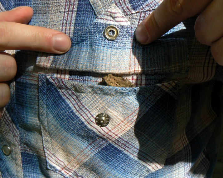 a man holds the pocket and ons up to his blue and white checked jacket