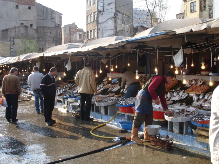 a man working in a fish market with men and women around