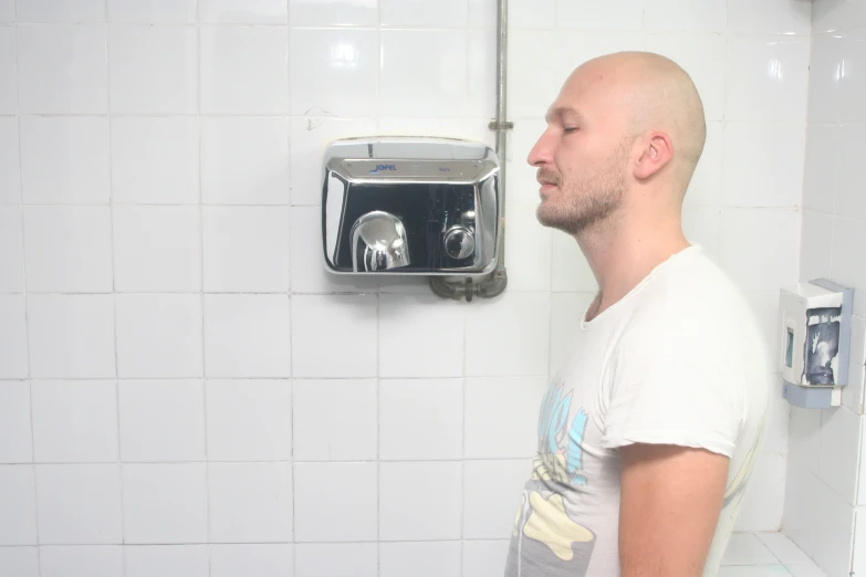 a bald man who has his head propped up against a shower head