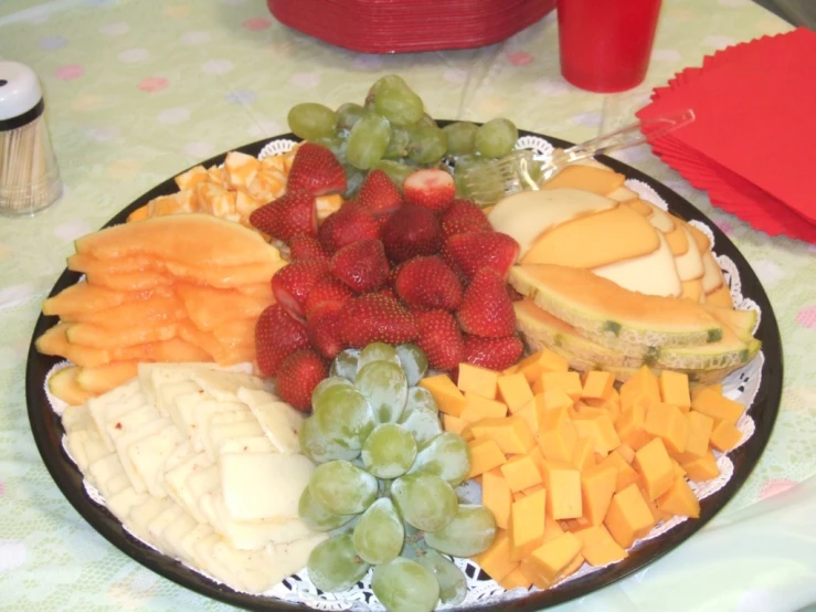 some cheeses, fruit and other food on a platter