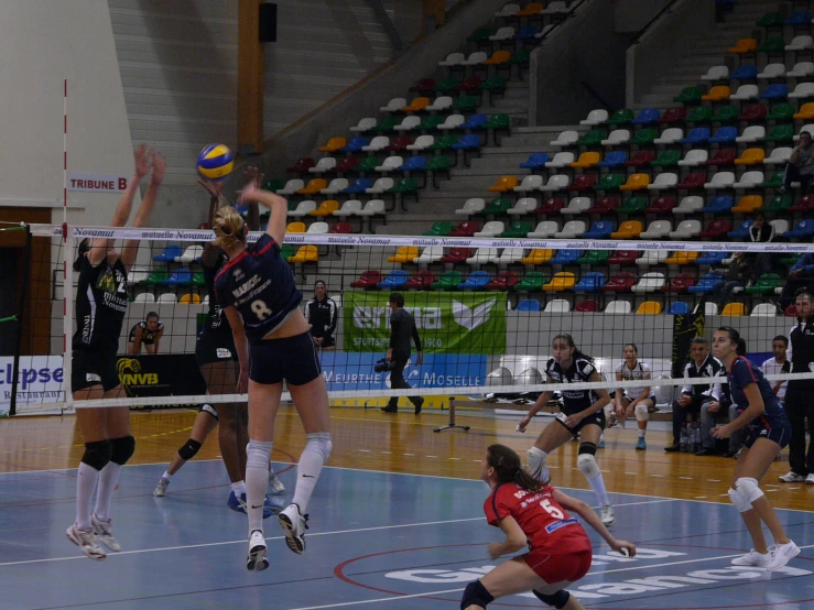 a group of women playing volleyball in a court