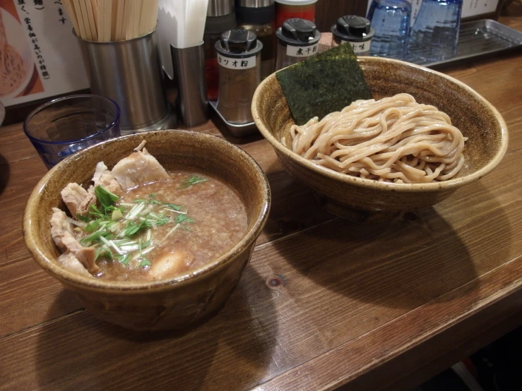 two bowls of soup on a table with chopsticks
