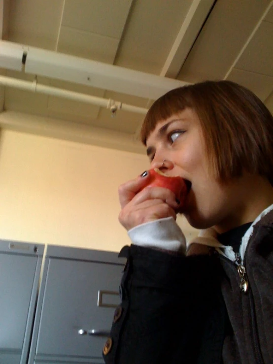 woman with red apple in mouth near lockers