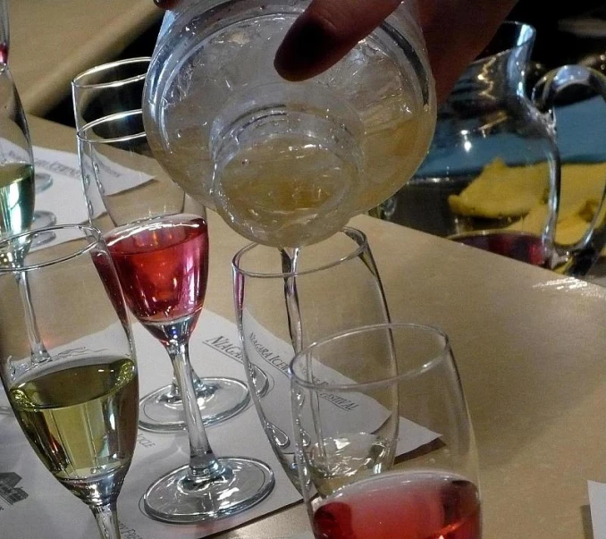 a person pouring wine in to various glasses