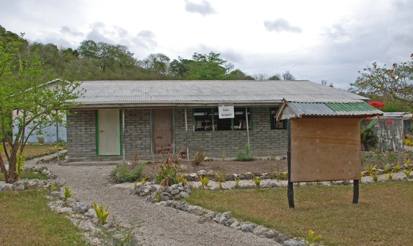 an abandoned home sits alone in a gravel yard