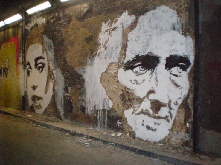a building wall with several portraits of many different people painted on it