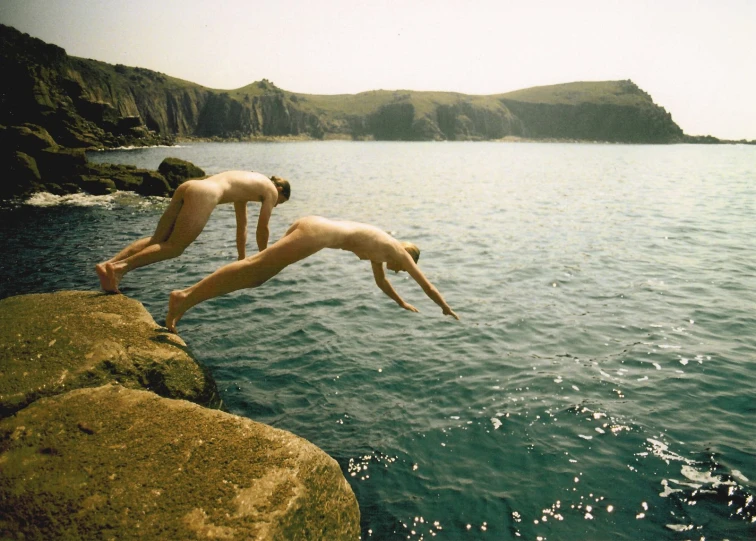 two women jumping off rocks into the water