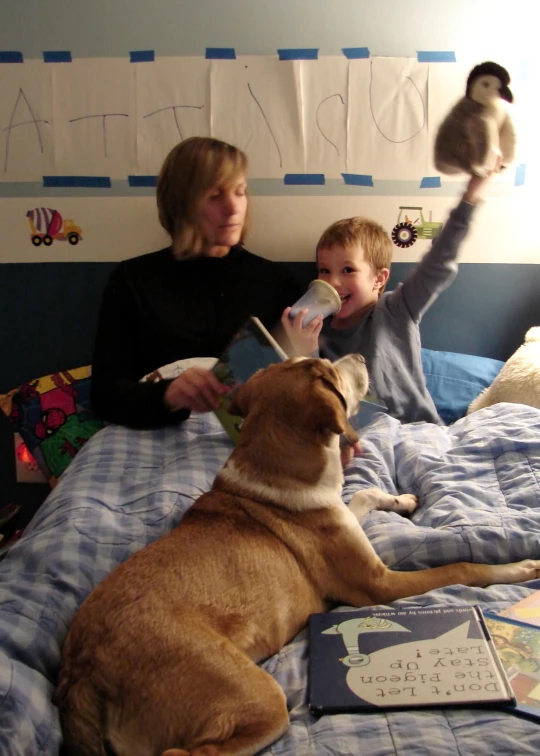 a woman and a little boy sitting on the bed with their dog