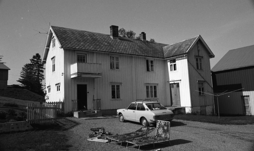 a white car parked outside a building with a man standing next to it