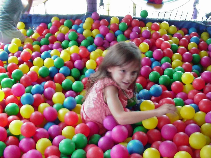 little girl playing in an obstacle filled with balloons