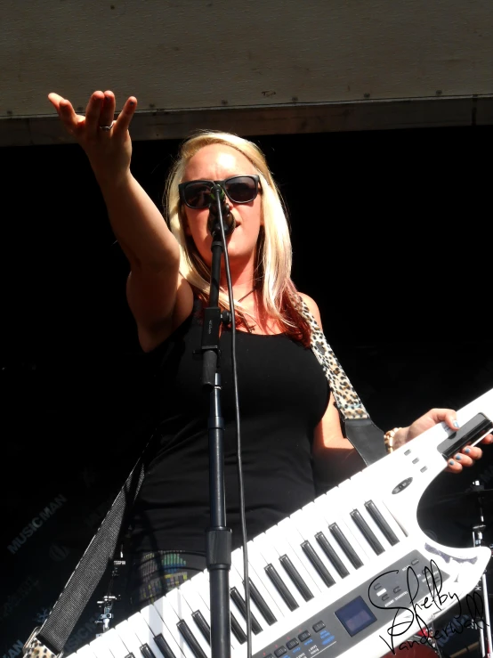 a woman standing at a keyboard while holding an instrument