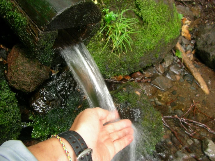 a hand is holding water coming out of a small pipe