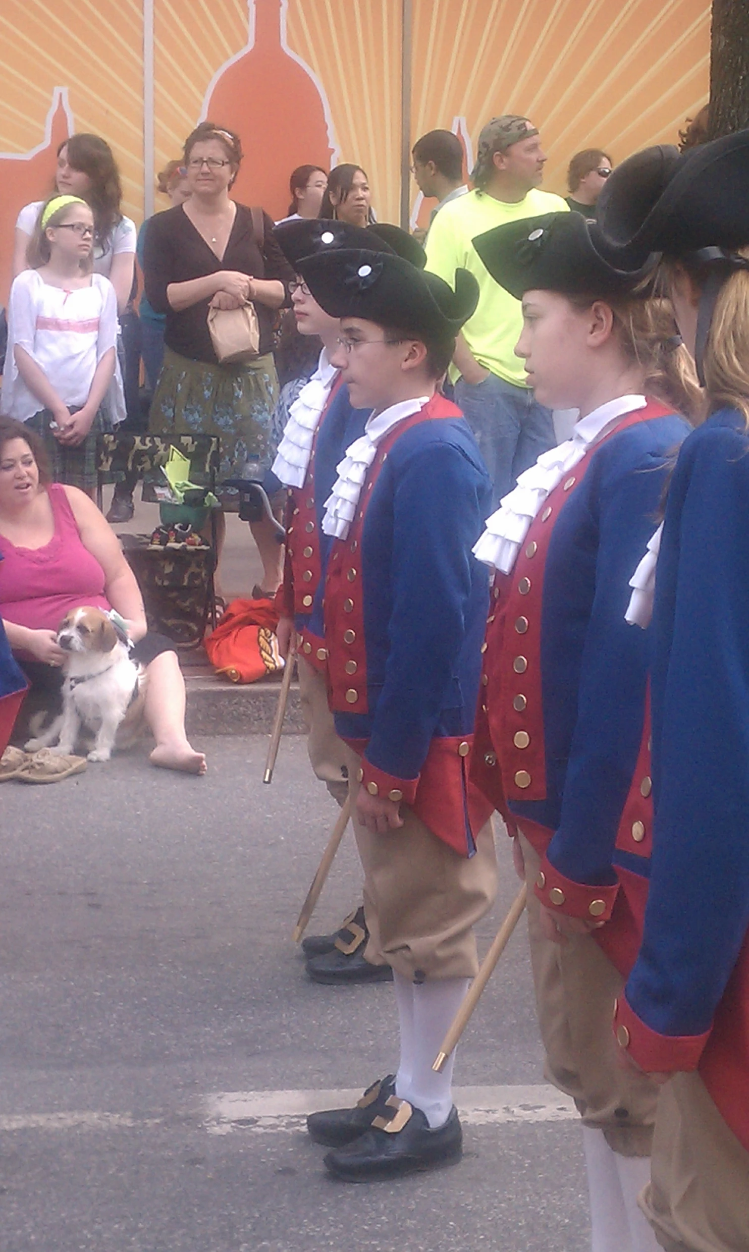 a boy in red jacket watching people on a street