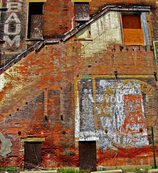 a large brick building with various pieces of graffiti on the side