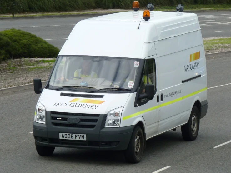 a small white van driving on the street