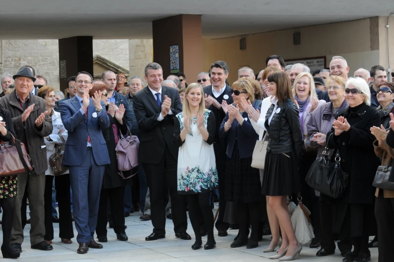 several people wearing suits and hats clapping outside