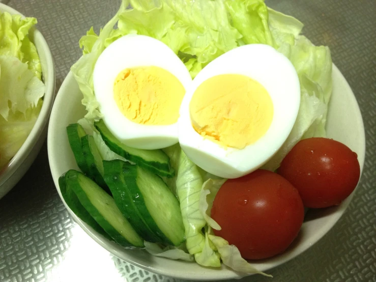 an egg, tomatoes and cucumber are in a bowl on the table