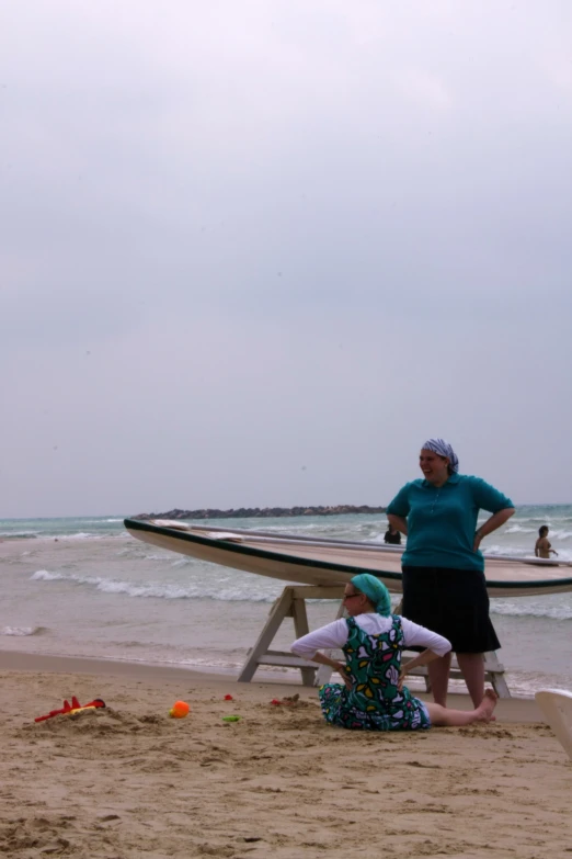 a woman standing on top of a beach next to a boat