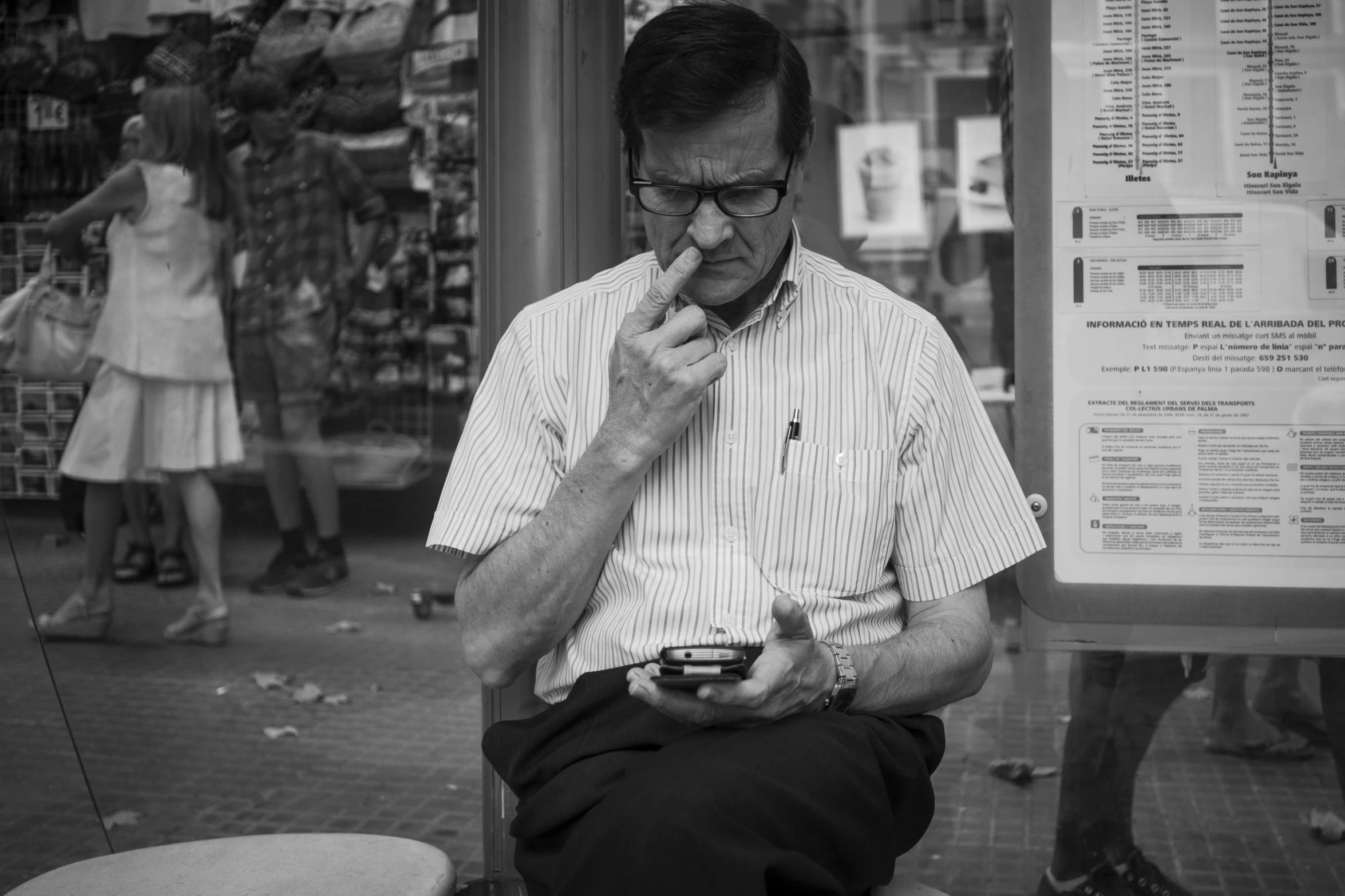 a man sitting on top of a bench holding a cellphone