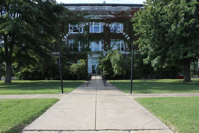 the entrance to the large building has trees on each side of it