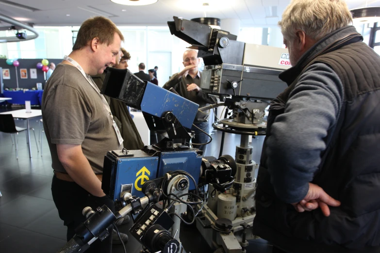 two men are standing by a camera in a room