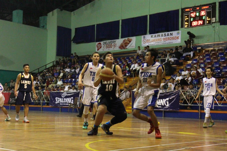 a basketball game in progress with the opposing team going up for the ball