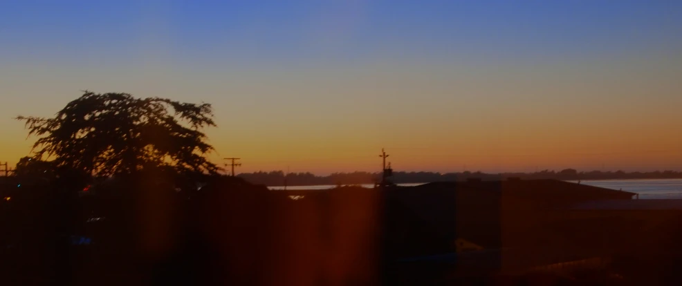 an orange glow appears on a sunset over a church and some trees